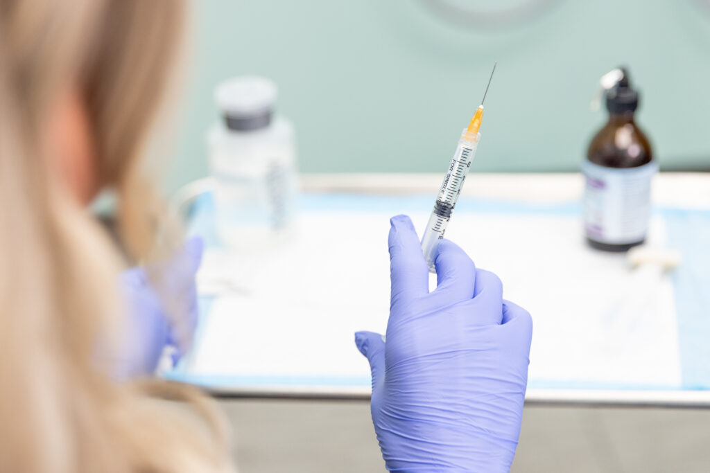 Chiropractor wearing gloves holds a syringe full of semaglutide, a treatment for medical weight loss near Iowa City.