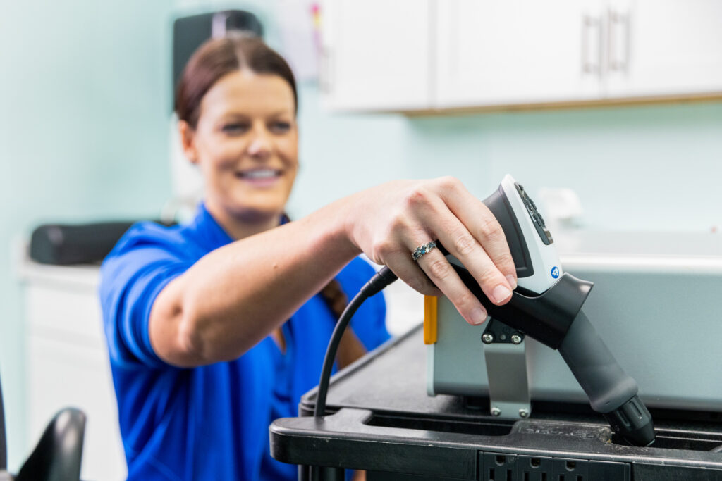 Chiropractor grabs a handheld device for cold laser therapy that is used as part of an anti-inflammatory treatment near Cedar Rapids.